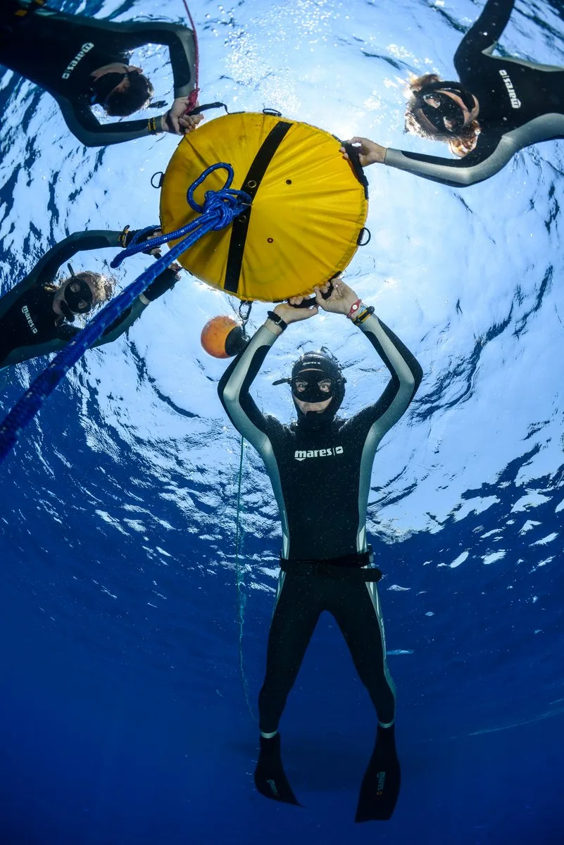 Freediving student holding the yellow buoy with the group